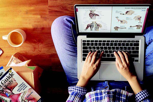 Overhead view of a person working on a laptop computer with textbooks from Books of Discovery nearby