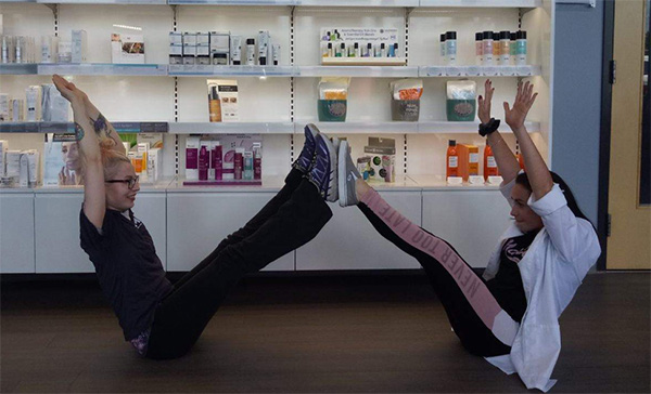 Two women on the floor forming a W with their bodies by putting their feet and arms up in the air