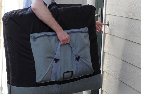 A mobile massage therapist with a portable massage table arriving at a client's home.