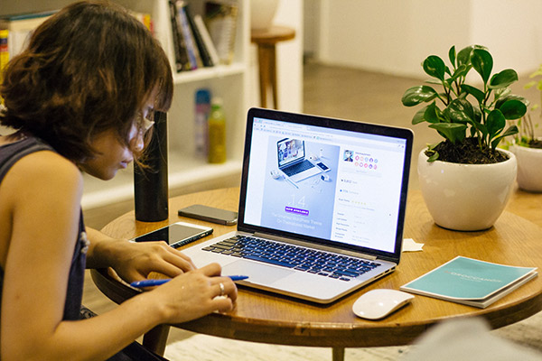 Young woman working at a computer with a notebook 