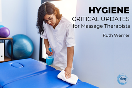 Massage therapist cleans a massage table.