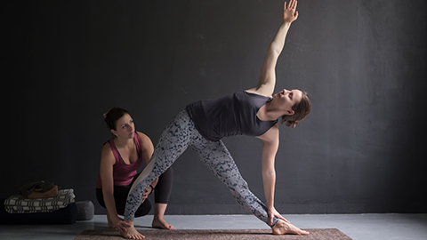 A woman performing an assisted yoga stretch 