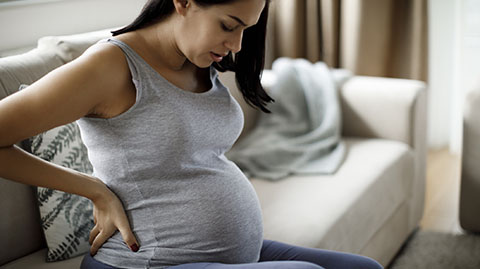 A pregnant woman looking down at her belly