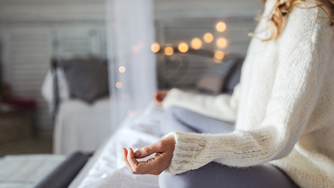 A woman sitting cross legged and meditating indoors