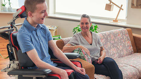 A mother looks lovingly on to her son who has ALS.