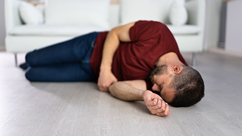 A man laying on the floor in front of a couch.