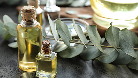 Two aromatherapy bottles on a table next to a sprig of sage