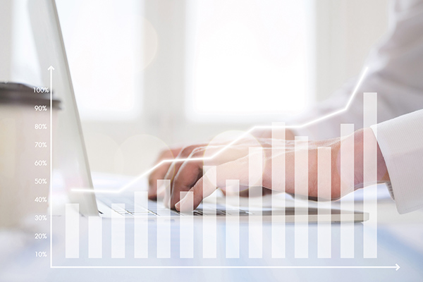 Bar graph superimposed over hands typing on a computer