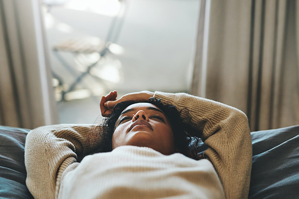 A woman lying on her back looking up at the ceiling in thought