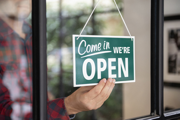 Man turning over Open sign in the window of his business