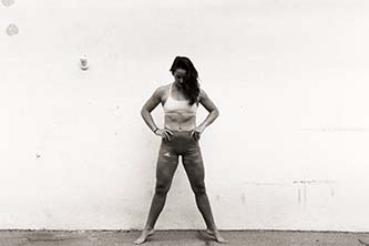 Black and white photo of a woman standing in front of a wall