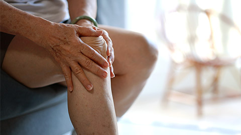 Image of an elderly man holding his right knee.