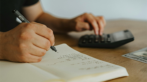 Image of a person using a calculator and notebook.