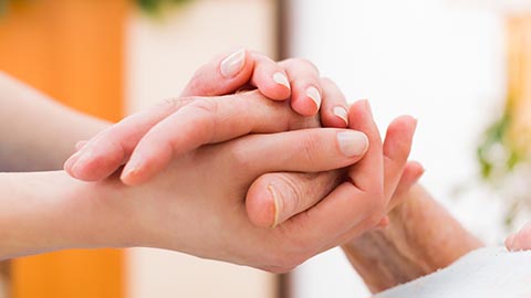 A young hand gently holding an older man's hand