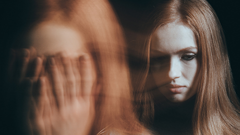 Young woman in emotional distress, covering her face with hands