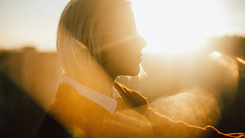 Young woman looking into the distance against a sunset 