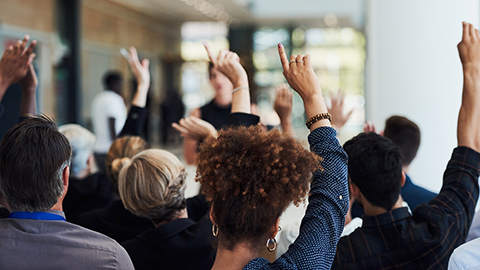 A classroom with students raising their hands