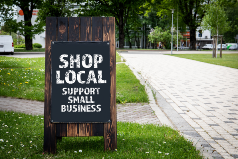 A sign supporting small businesses displays near a walkway.