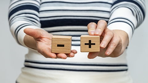 Image of a person holding wooden blocks with plus and minus symbols.