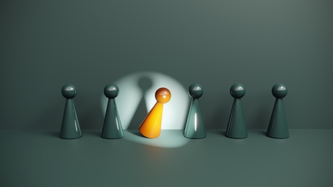 A single orange figure steps forward under a focused spotlight while identical figures remain in the background.
