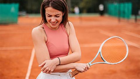 Image of a person holding their elbow while playing tennis.