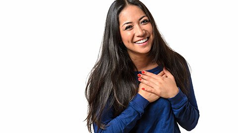 A woman holding her hands to her heart and smiling