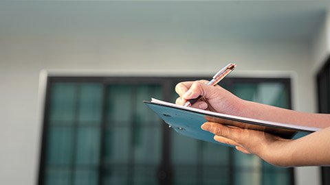 A person holding a clipboard taking notes in the right frame of a photo.