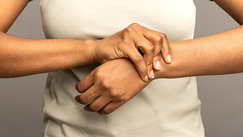 A woman holds her wrist due to joint pain.