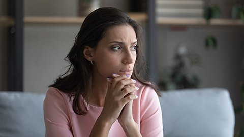 A woman with her hands clenched looking in the distance.