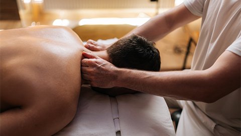 A man laying face down on a massage table receiving a massage.