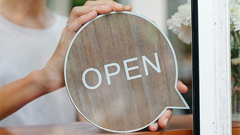 an image of a person holding a wooden farmhouse open sign.