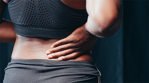 A woman holding her lower back in pain.