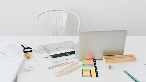 A white desk with office materials spread across the table.