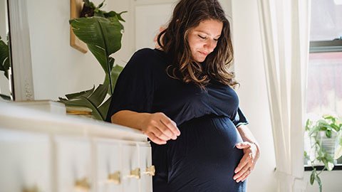 Pregnant woman smiling and touching her belly