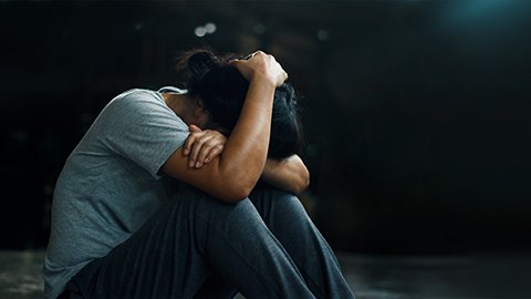 Black woman sitting on ground in despair with her head in her hands