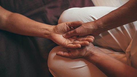 Black massage therapist massaging the hand of a Black client